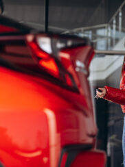 woman-standing-by-her-new-red-car